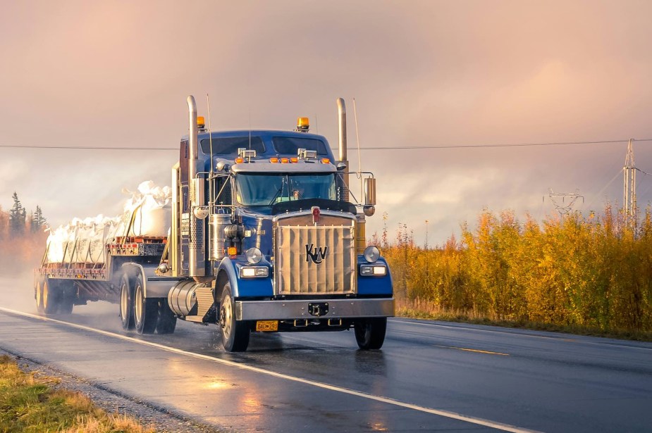 Semi truck driving along rural road.