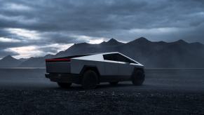 A Tesla Cybertruck in the desert under clouds.