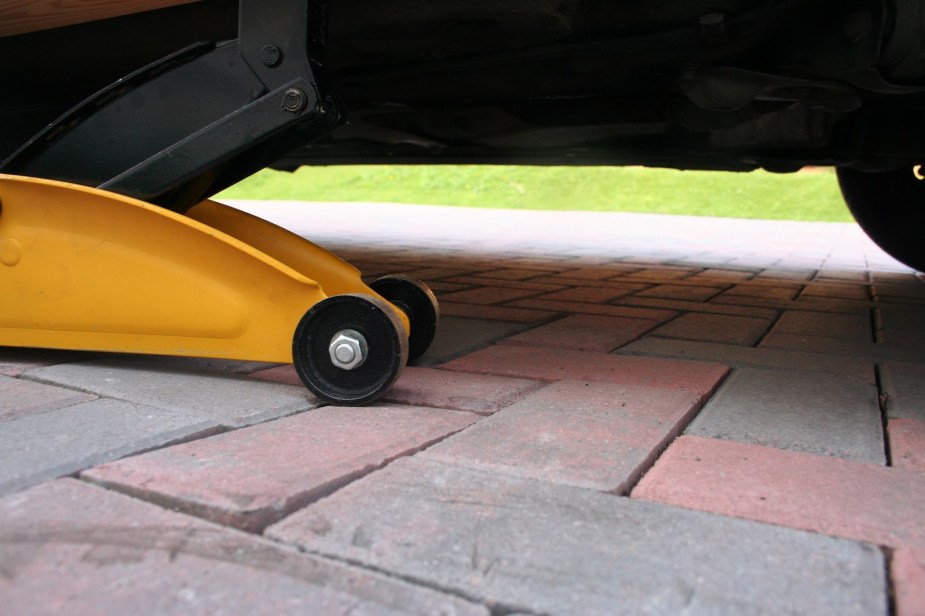 Yellow trolley jack beneath a pickup truck.