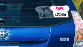 A blue Toyota Prius flashes its stickers reporting that it drives for Uber and Lyft.