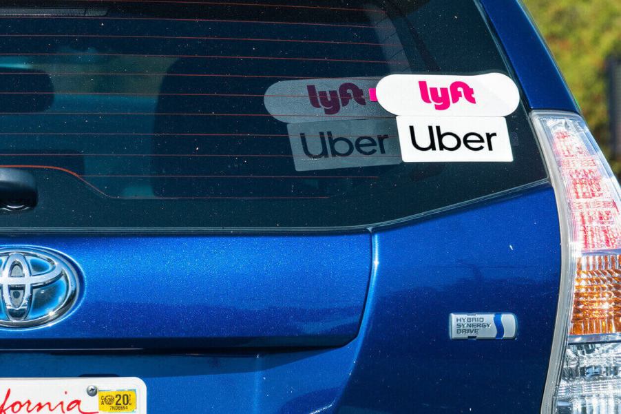 A blue Toyota Prius flashes its stickers reporting that it drives for Uber and Lyft.