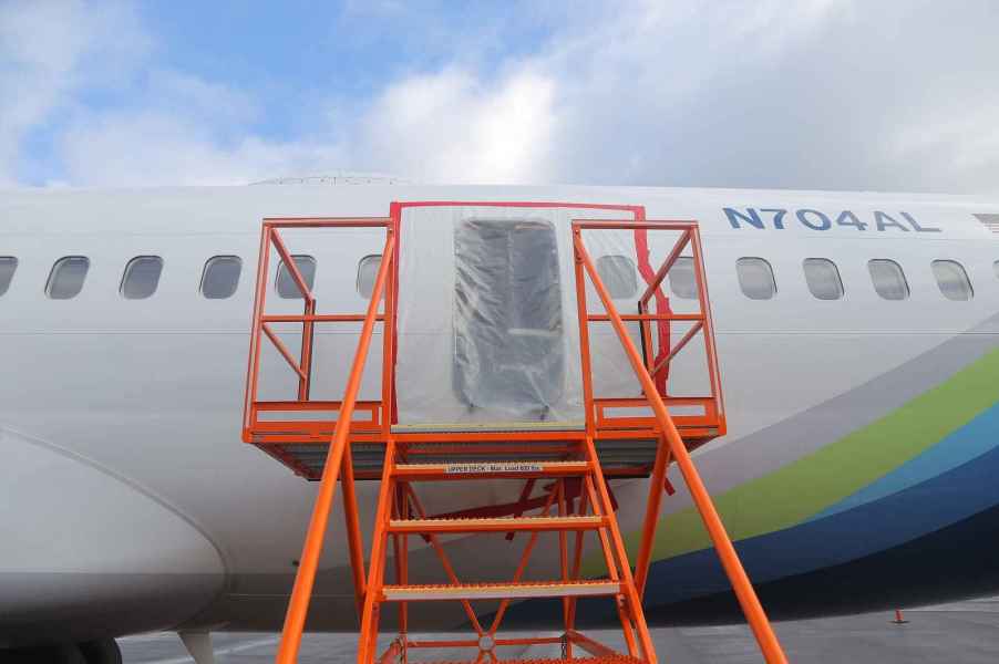 The left MED plug on Alaska Airlines Flight 1282 shown covered in a plastic sheeting with an orange metal staircase positioned in front of it