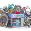 A rendering of an auto parts store surrounded by many car parts including clutch, oil filters, pistons, a turbo, spark plugs, and more