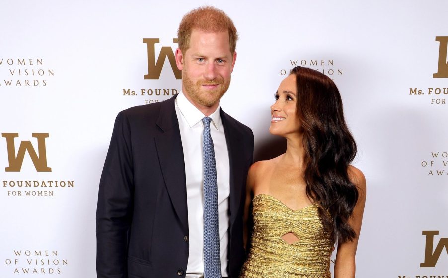 Meghan Markle and Prince Harry photographed attending an NYC event on May 16, 2023 a paparazzi police chase would follow Meghan wearing gold dress Harry in a suit with blue tie