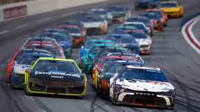 NASCAR cars are shown with Denny Hamlin, driver of the #11 FedEx Toyota, and Austin Cindric, driver of the #2 Menards/Knauf Insulation Ford, lead the field during the NASCAR Cup Series Ambetter Health 400 at Atlanta Motor Speedway on February 25, 2024 in Hampton, Georgia.