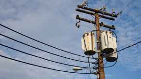 A telephone pole is shown with cables strung across a cloudy sky