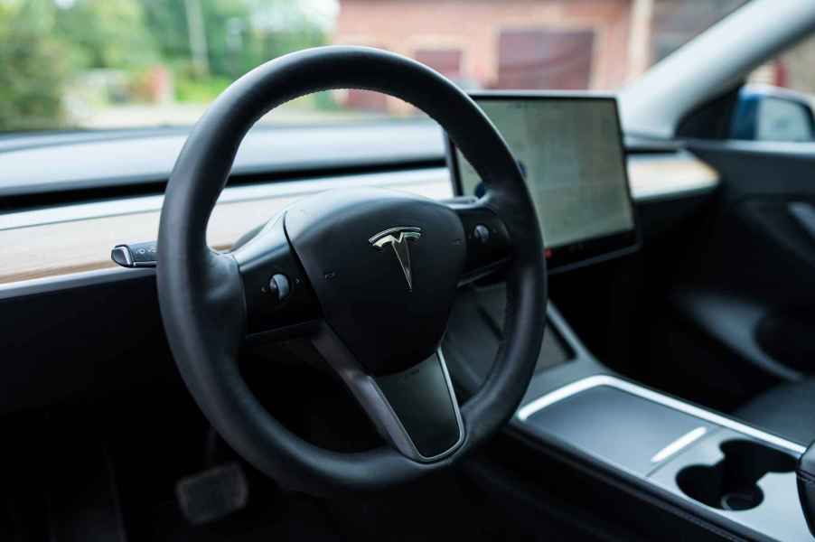 A black Tesla steering wheel is shown in close up