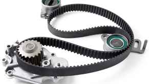 Car engine timing belt kit components are laid out on a white surface