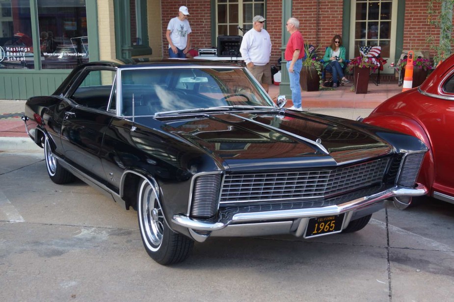 Black Buick muscle car parked in front of a building during a mainstreet car show.