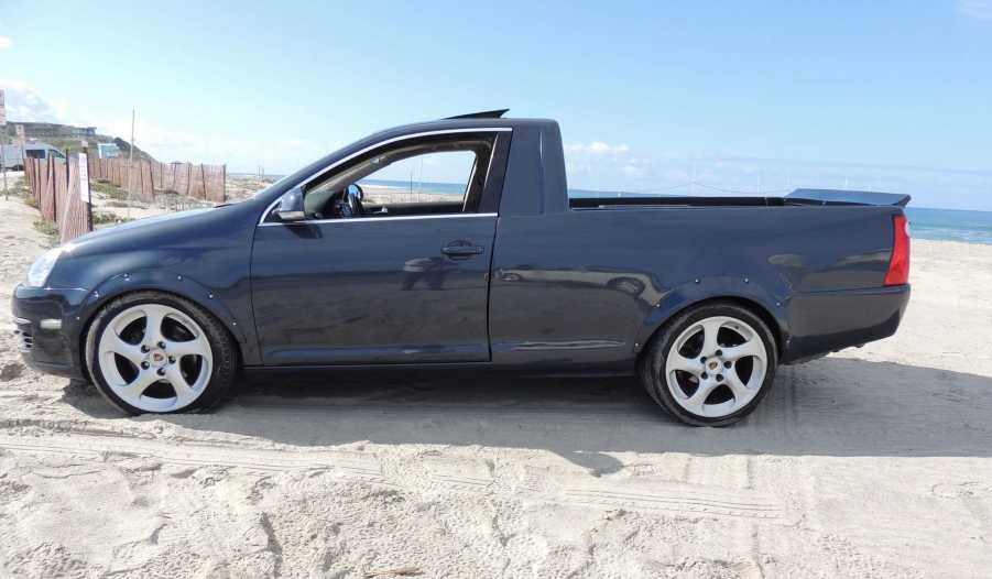 Side view of a modified VW Jetta pickup truck parked on a beach.