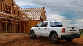 White electric Ram pickup truck parked in front of a construction site.