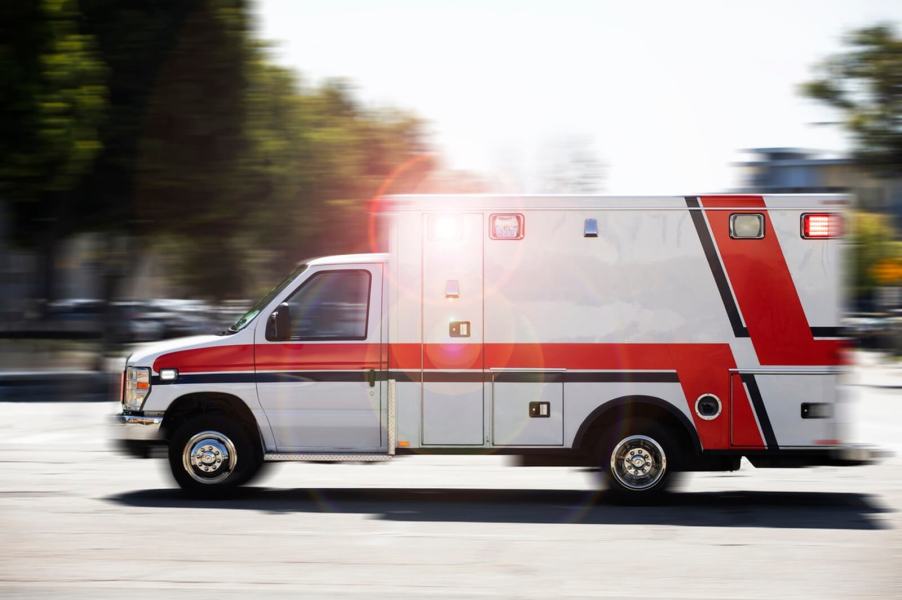 An operator drives an ambulance with sirens and lights used to clear traffic.