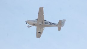 Underside of an ultralight white aircraft against a blue sky.