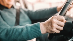 An older man drives his car.