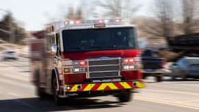 Red fire truck races down a suburban street to a house fire.