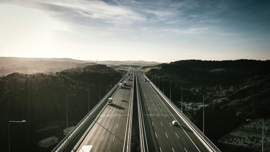 Multiple cars driving down a divided highway bridge.