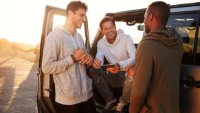 Millennials smile next to their parked SUV.