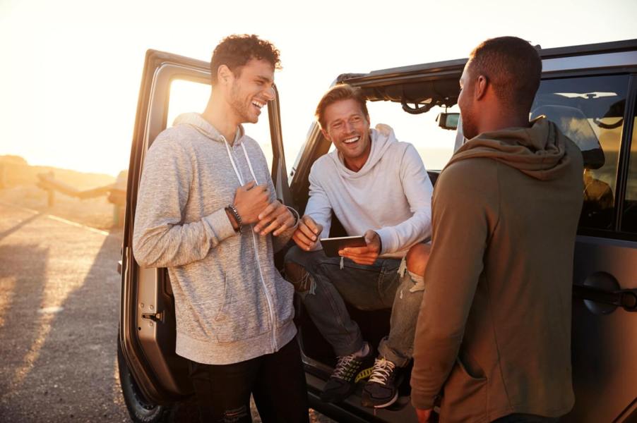 Millennials smile next to their parked SUV.