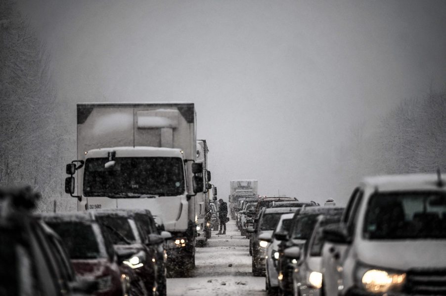 Cars and a bakery truck stuck on a highway during a snow storm.