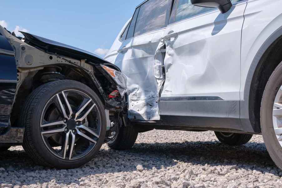 A car accident with a white SUV right rear side view after a black car crashes into it close view