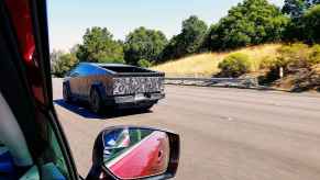 A camouflaged Tesla Cybertruck photographed while driving through a car's passenger front window