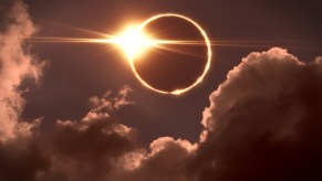 The sun disappearing behind the moon in a total solar eclipse, clouds visible in the foreground