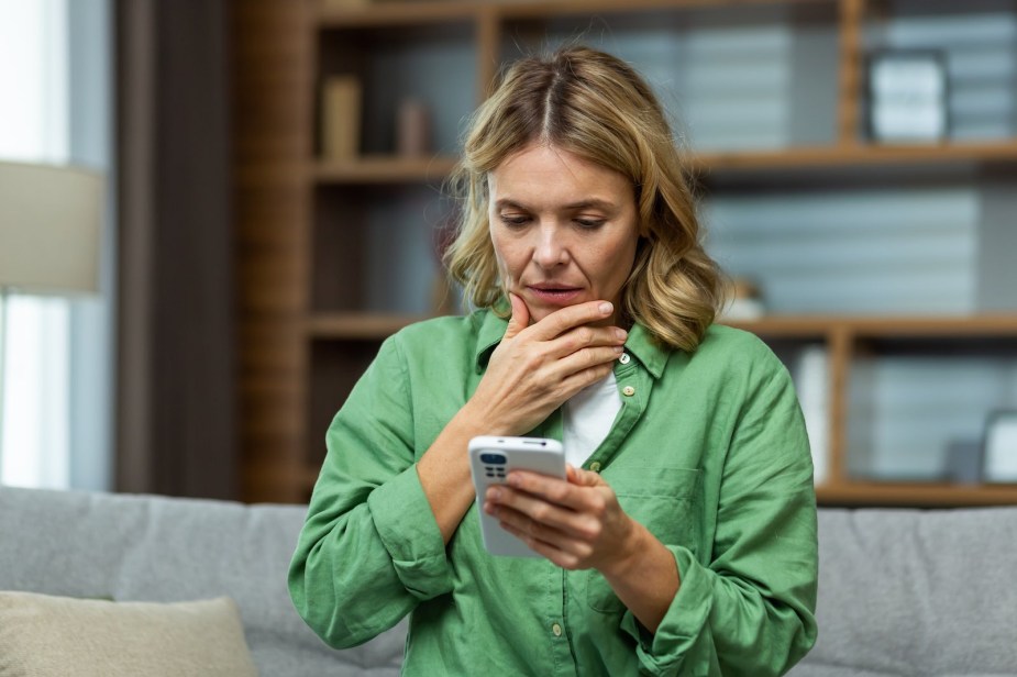 Woman stares at her ringing phone as she gets a telemarketing call.