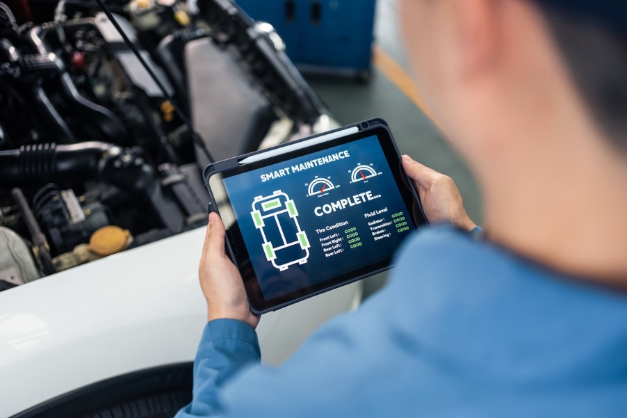 Technician uses a tablet computer to read the onboard diagnostics OBD II check engine codes of a car