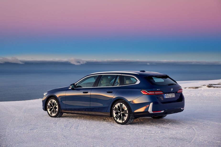 BMW wagon parked on a beach in front of the sunset.