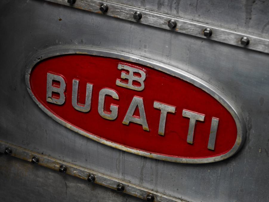 The red Bugatti logo stamped on the side of a metal engine block.