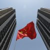 A red Chinese flag between two skyscrapers.