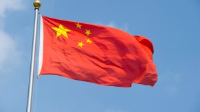 China's red flag with yellow stars flying in front of a blue sky