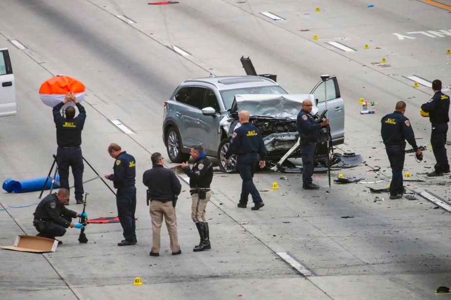 Police officers surround SUV parked on the highway after crash.