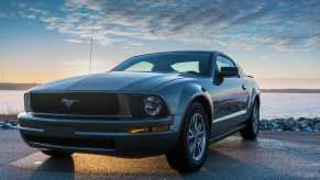 Gray Ford Mustang parked in front of a lake.