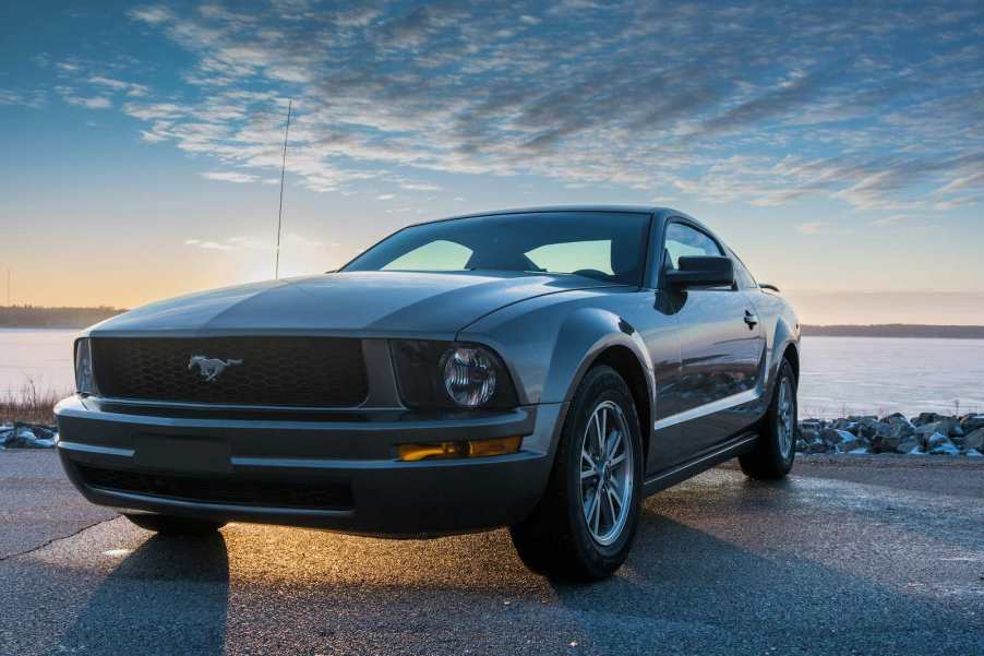 Gray Ford Mustang parked in front of a lake.