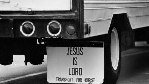 White semi truck trailer with white "Jesus is Lord" mudflaps hanging behind its tires