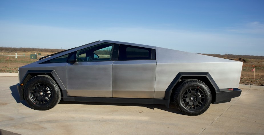 Metal Tesla Cybertruck parked on a pavement lot.