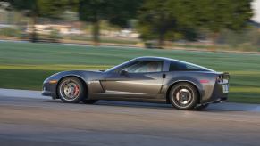 A gray Chevrolet Corvette Z06 shows off its side profile as it cruises down a road.