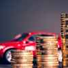 A red toy car shown blurred behind a stacks of gold coins