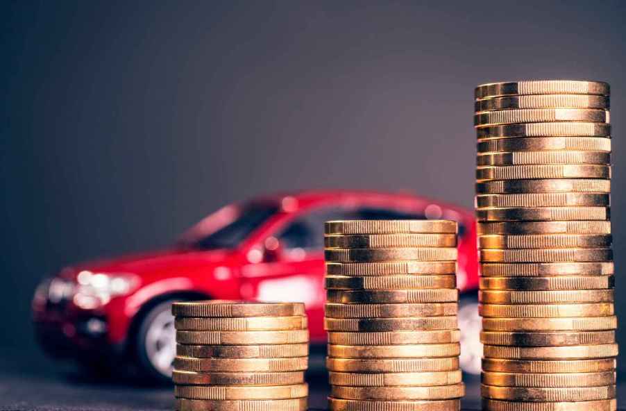 A red toy car shown blurred behind a stacks of gold coins