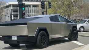 A Tesla Cybertruck shown turning right part a traffic light in right rear angle view