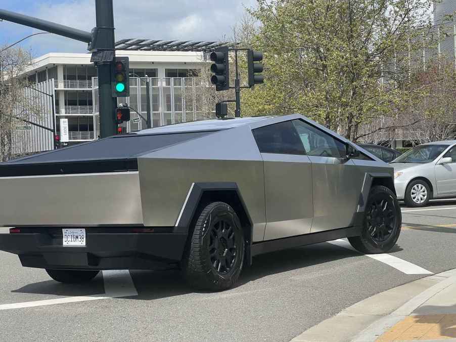 A Tesla Cybertruck shown turning right part a traffic light in right rear angle view