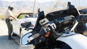 A California Highway Patrol Officer dispenses a ticket after getting off a motorcycle.