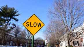 An orange diamond "SLOW" sign on a residential street