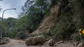 A mountain road in Hualien County, Taiwan blocked by rockfall and fallen debris large boulder in center of road street lamp in left frame