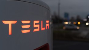 Tesla supercharger in very close top view at night with "Tesla" logo backlit in orange lighting