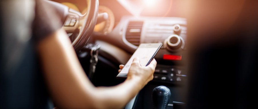 Woman's arm holding a cell phone while driving