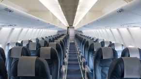 The empty cabin of a commercial plane blue seats with cabin lights turned on