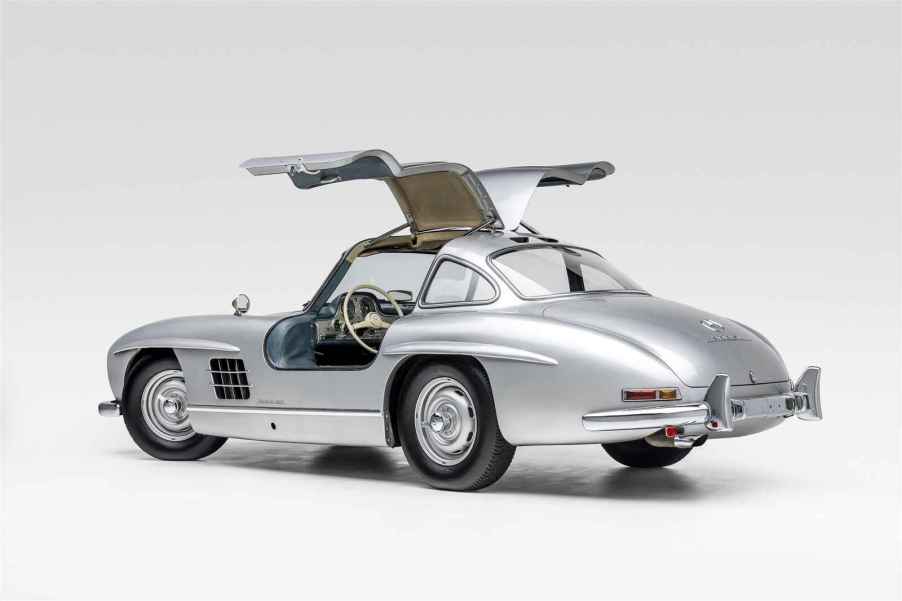 A silver 1955 Mercedes-Benz 300SL Gullwing with doors open parked in left ear angle view on white surface white background