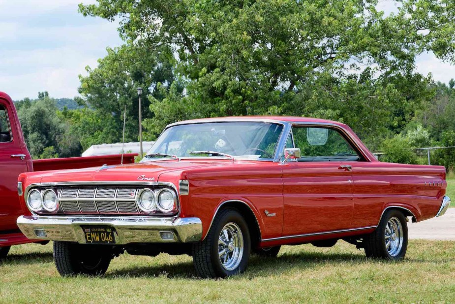 Bright red Mercury Comet muscle car parked in a field at an auto show.